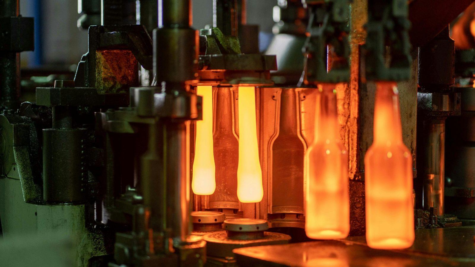Glass bottles being formed on a production line, glowing orange