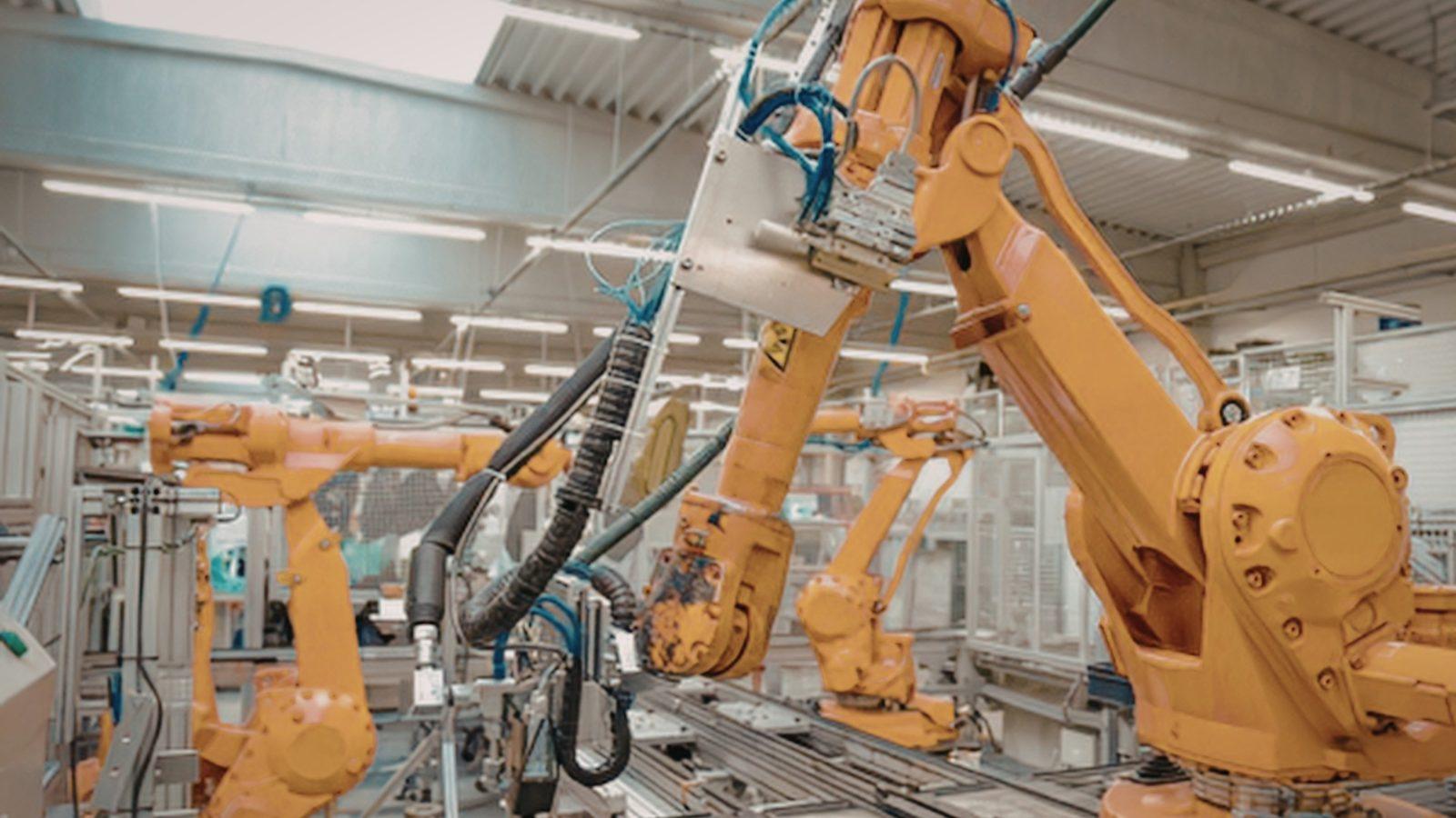 Industrial robot arms clustered over an automotive production cell